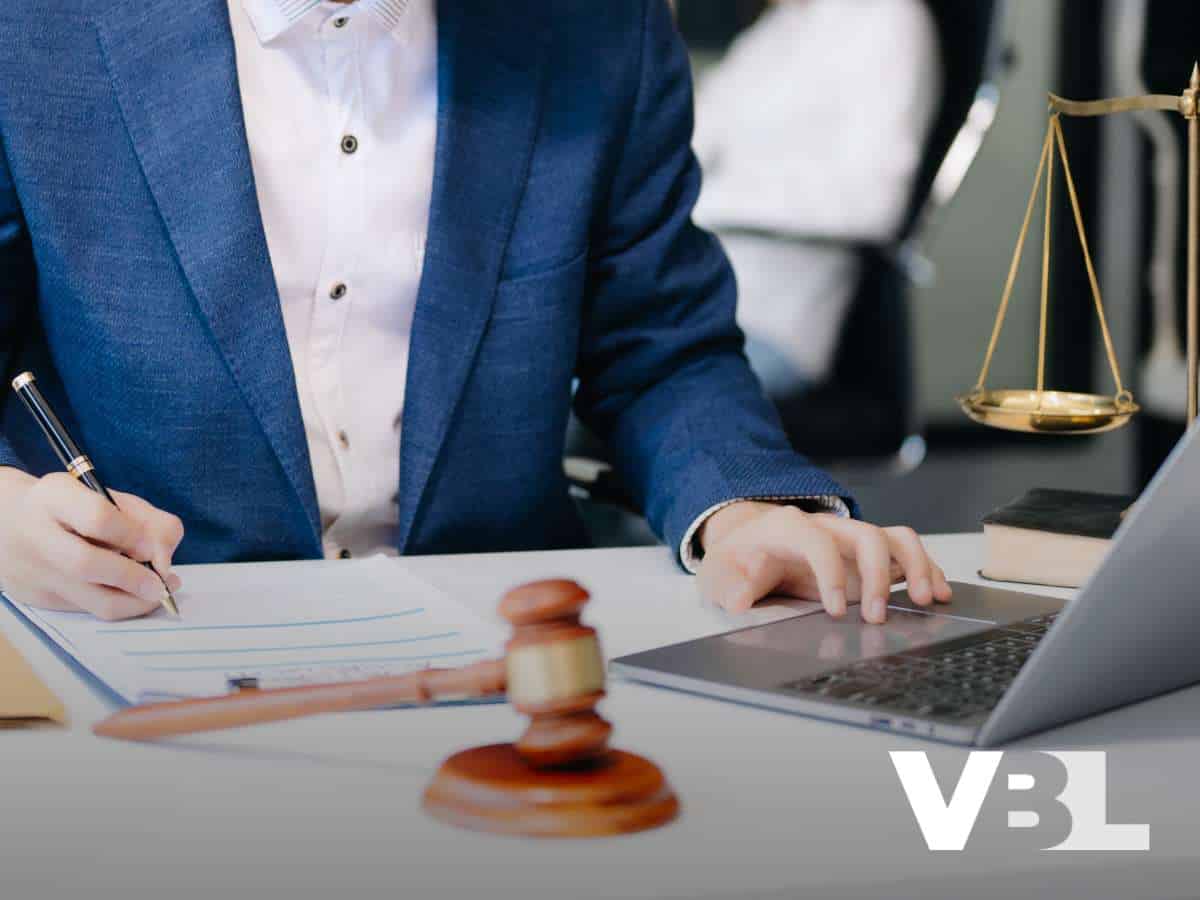 A bankruptcy lawyer reviewing documents at a desk with a gavel, scales, and laptop